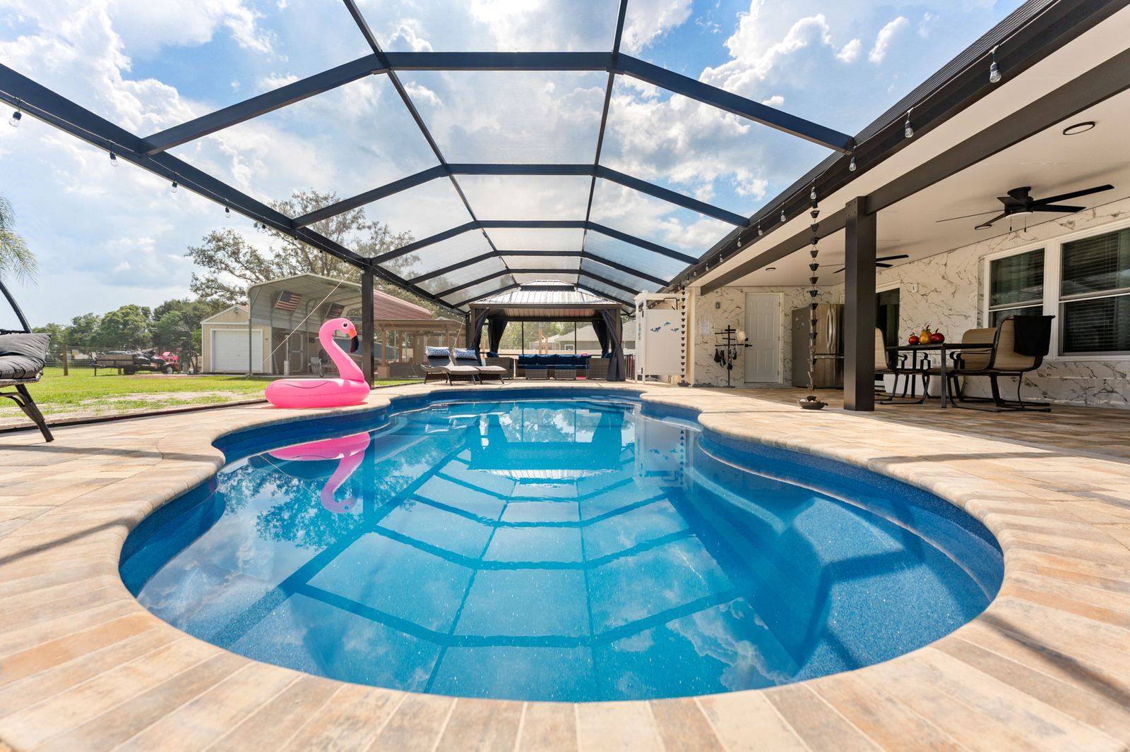 Freeform pool under a screened lanai with a flamingo float