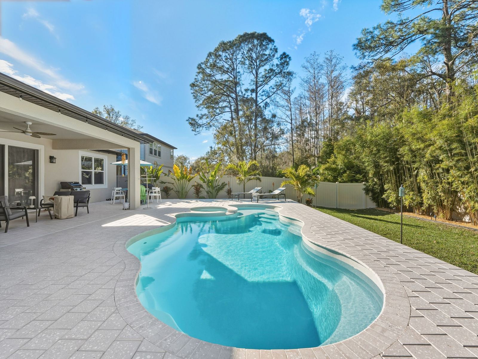 Freeform pool with a sun shelf and spa, tall pines behind