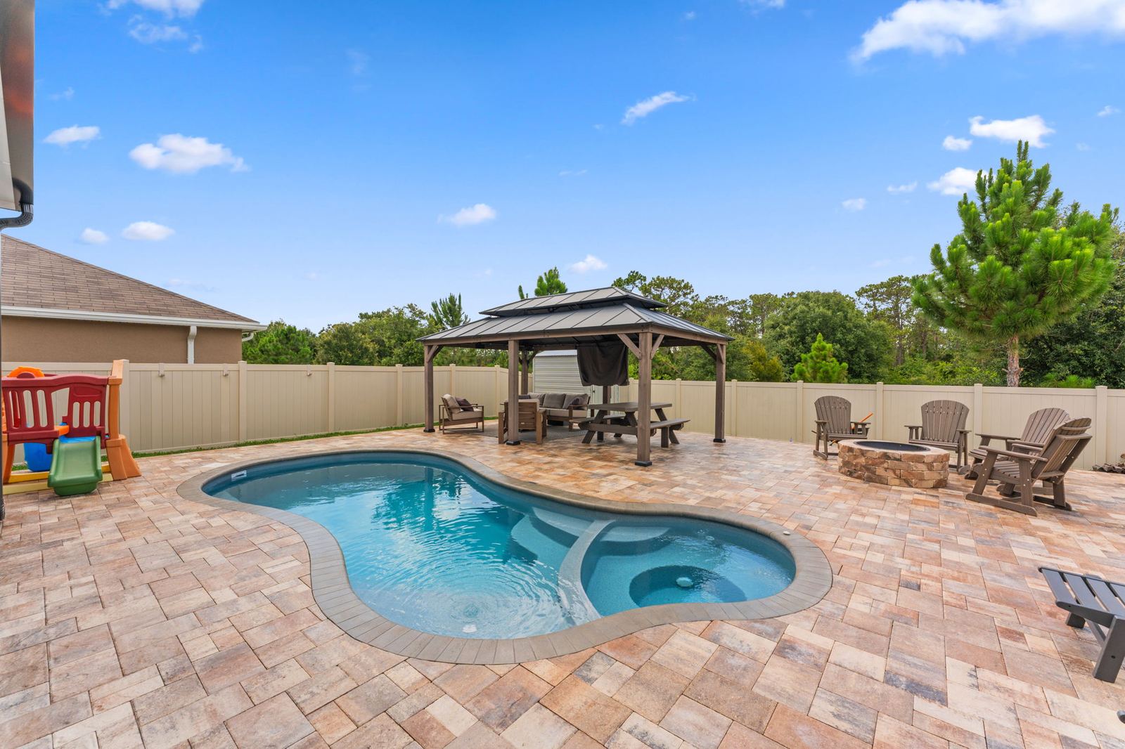Freeform pool with an attached spa, paver patio and gazebo