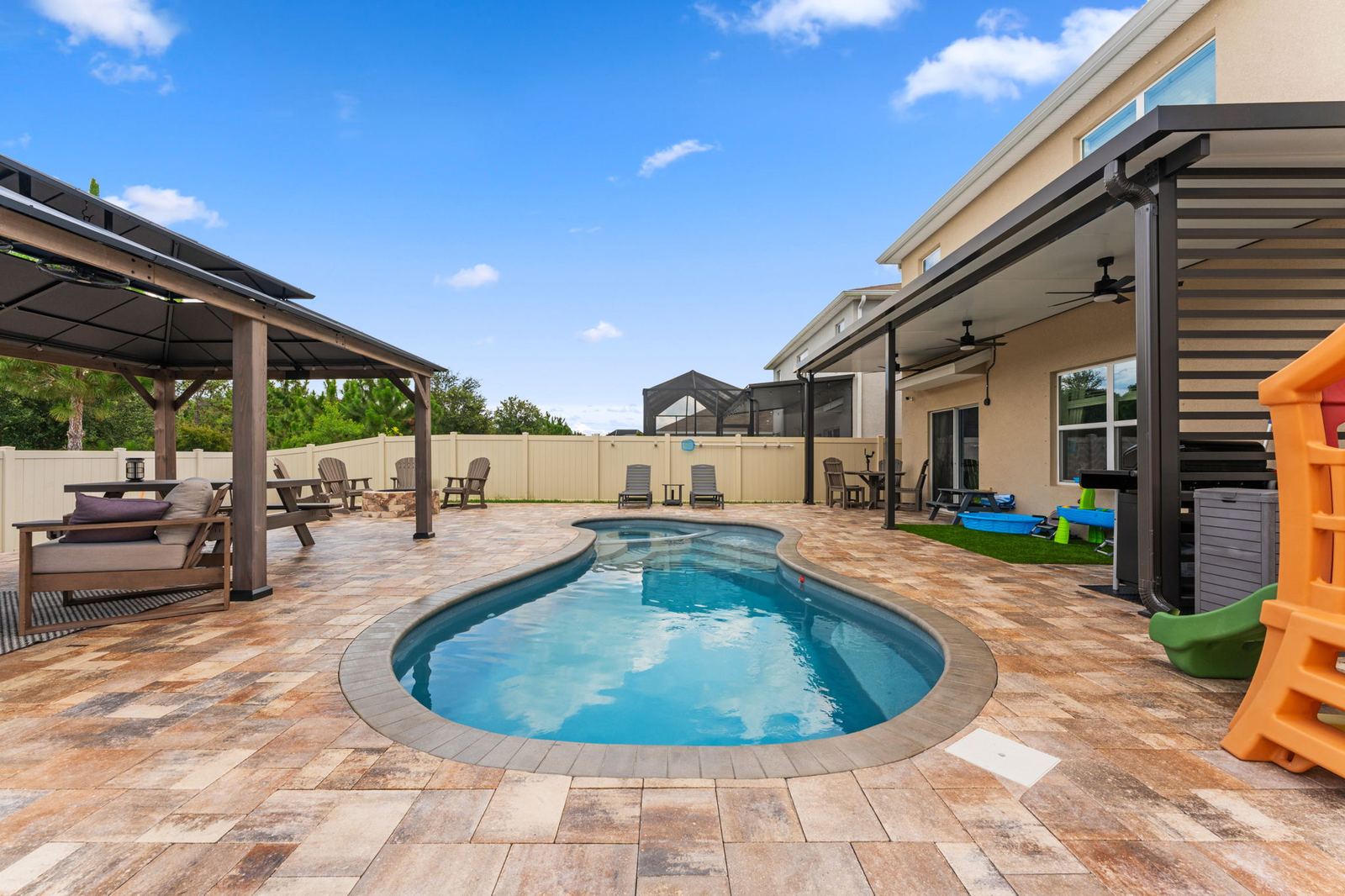 Freeform pool with a paver patio and covered outdoor seating